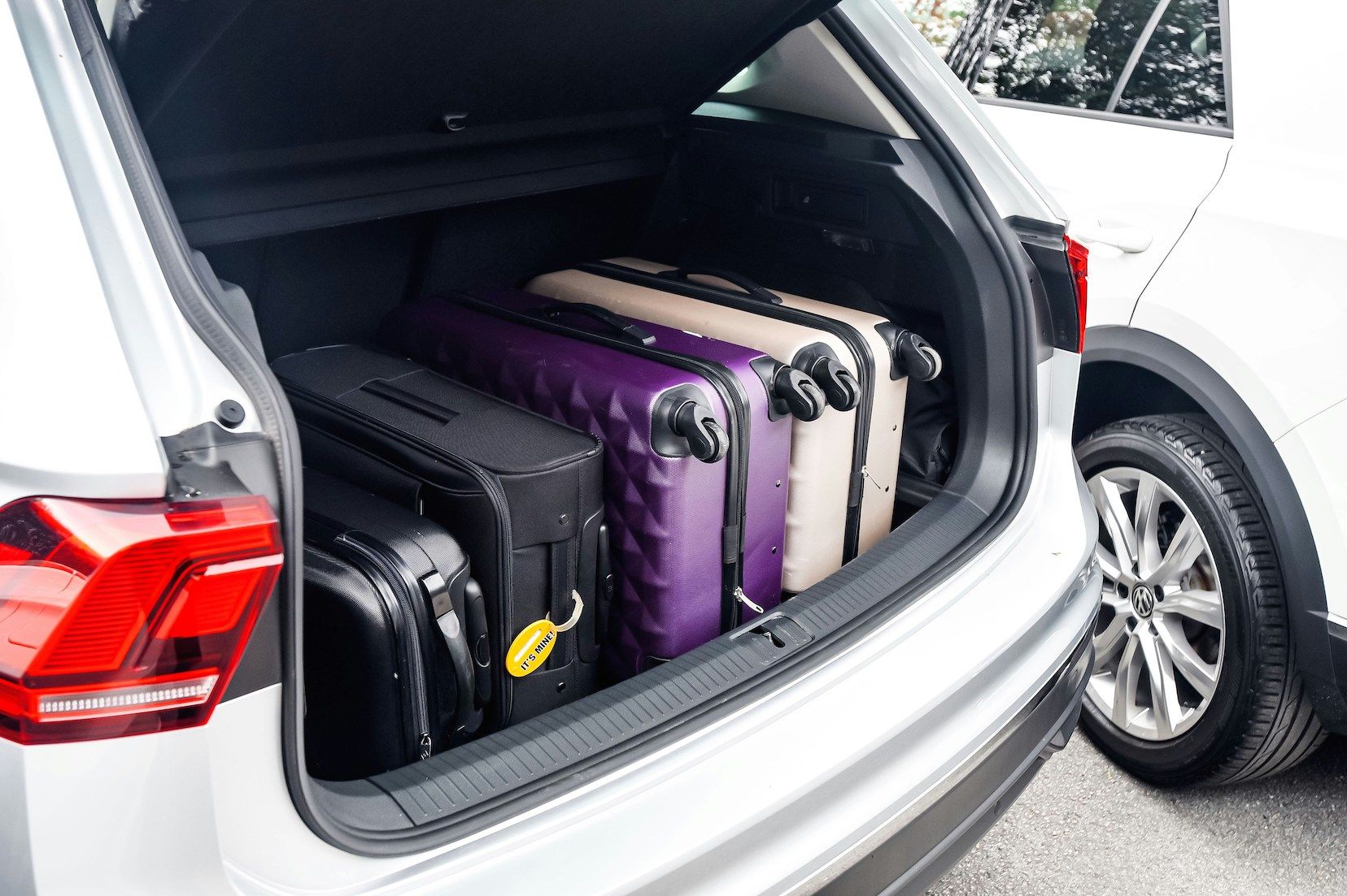 Open car trunk driving in Spain and Portugal filled with suitcases, two black, one purple, and one beige