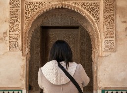 Brunette woman standing in front of arabic style architecture in Spain