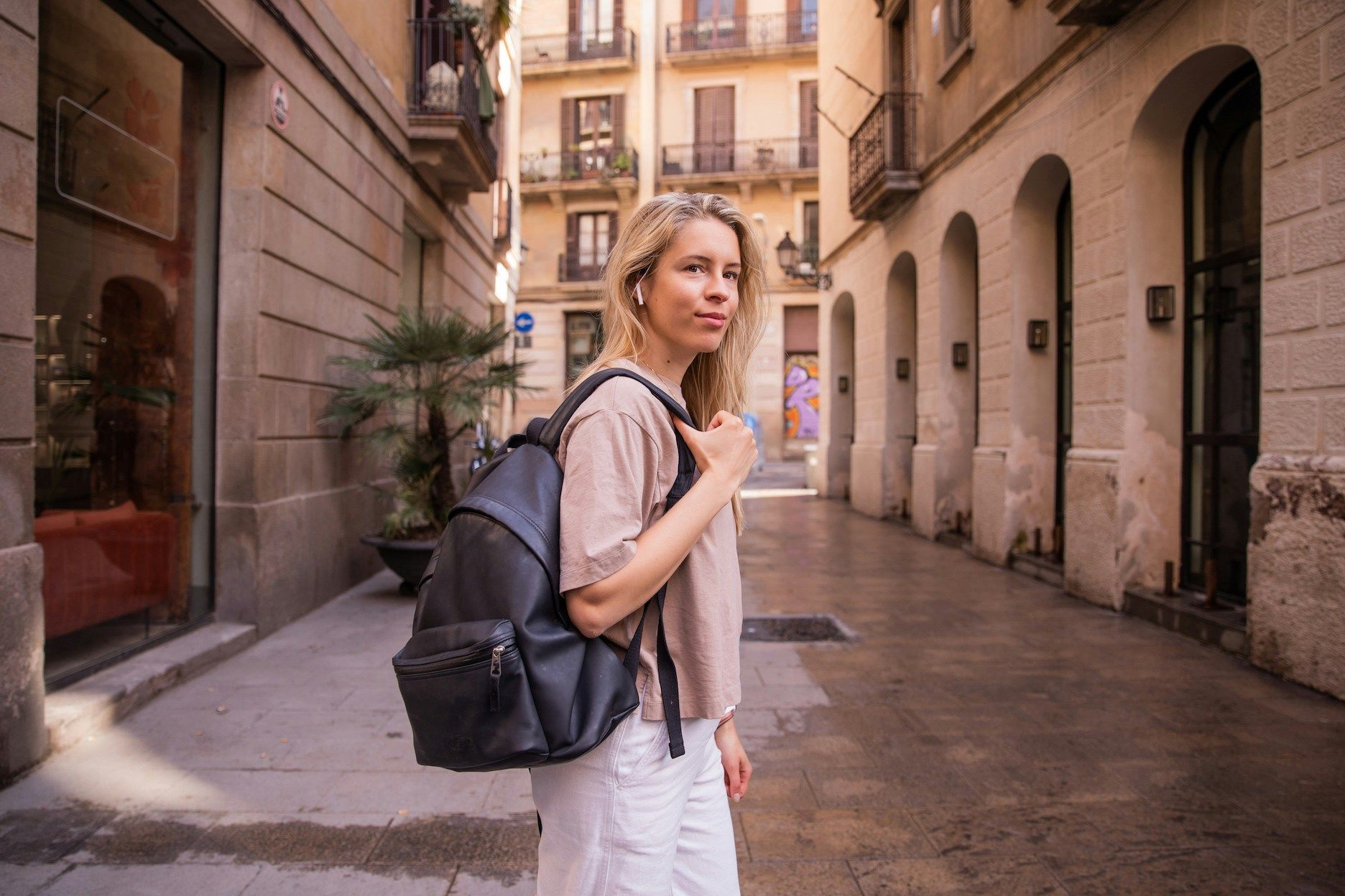 Blonde woman with backpack standing in street in Spain