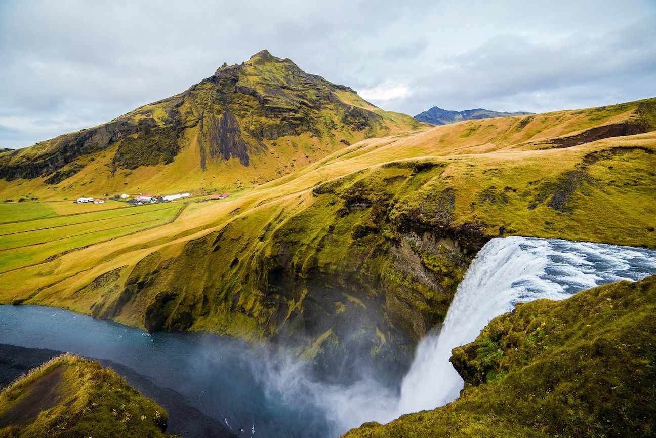Waterfall falling from yellow-green mountain cliffs in Iceland