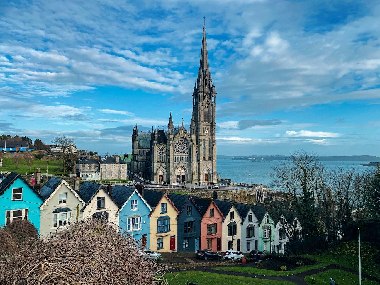 Colorful houses with gothic cathedral towering in the background along the water in Ireland