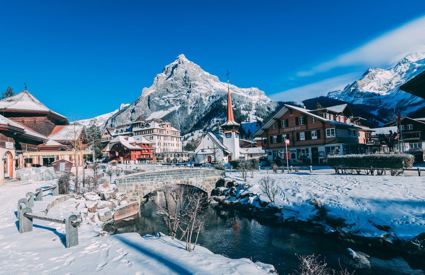 Snowy Swiss village, frozen lake and snow-capped mountains
