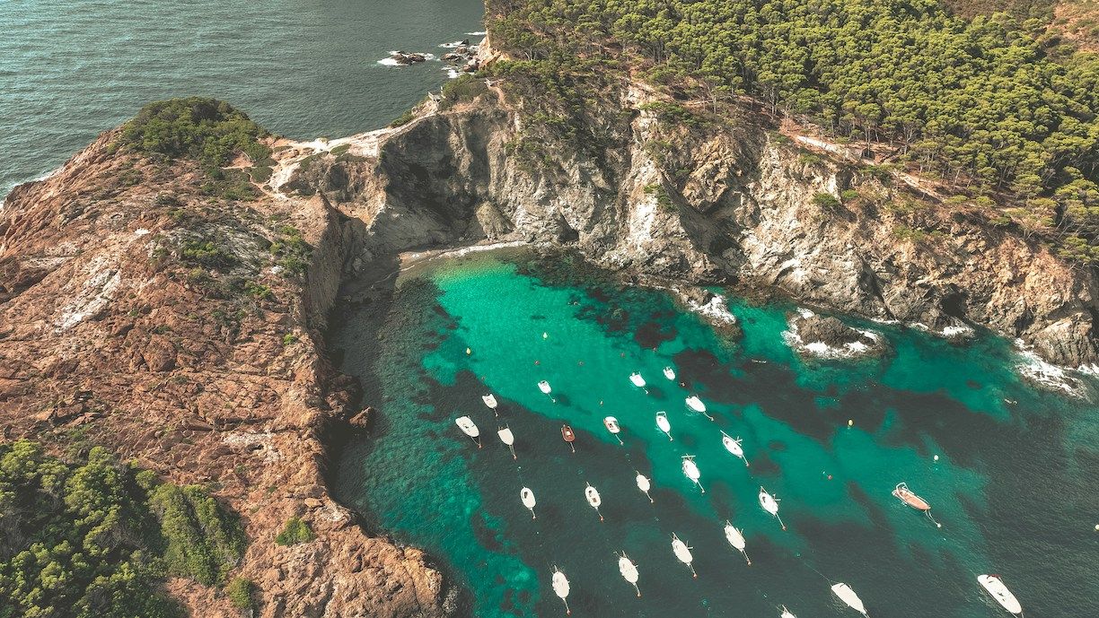 Boats parked in turquoise waters in cove in Costa Brava, Spain