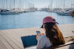 girl by port with laptop and cell phone