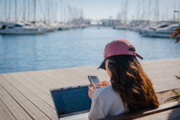 girl by port with laptop and cell phone